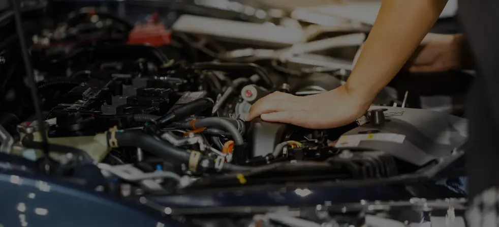 A technician works on a car engine, addressing the problem indicated by the Check Engine Light.