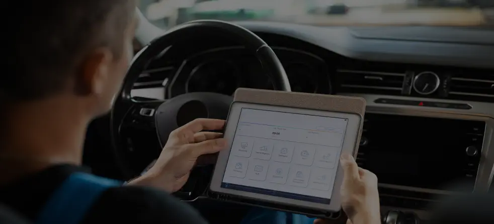 A person engaged with a tablet, emphasizing the need for software updates and programming in modern vehicles.