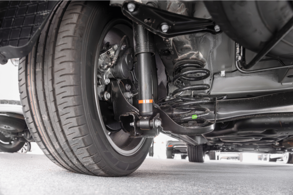 Suspension, auto repair in Milwaukee, WI at Next Level Auto Services. Underside view of a car showing suspension components, coil spring, shock absorber, and tire.